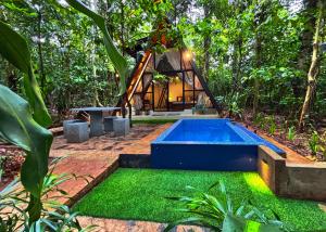 une maison dans la forêt avec une piscine dans l'établissement Kandy Little White House Cabanas, à Kandy