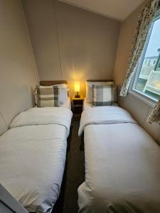 two beds in a small room with a window at Rendezvous at Ocean Edge in Heysham