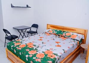 ein Bett mit einer geblümten Tagesdecke, zwei Stühle und ein Tisch in der Unterkunft Studios cosy in Aoudja