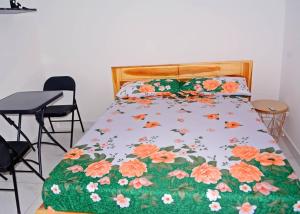ein Bett mit einer geblümten Tagesdecke, dazu ein Tisch und Stühle in der Unterkunft Studios cosy in Aoudja + 4 Fotos