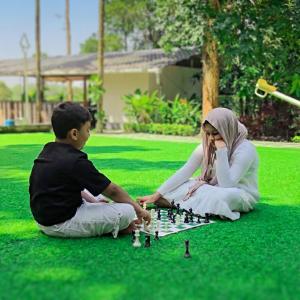 a man and a woman playing chess on the grass at Nellar Dream Resort in Meppādi +1 photo