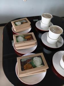 four plates of food on a black table with cups at Hotel Grand illa palopo in Palopo