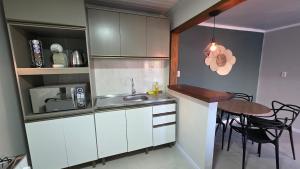 a kitchen with white cabinets and a table and a dining room at Casa completa, lindamente decorada, nova com 2 quartos in São Gabriel