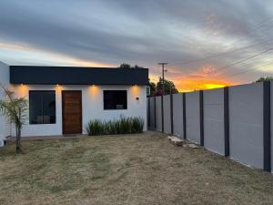 a white house with a fence and a sunset at Casa completa, lindamente decorada, nova com 2 quartos in São Gabriel