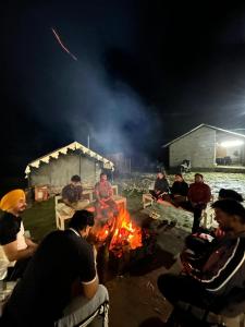 eine Gruppe von Menschen sitzt um ein Feuer herum in der Unterkunft Parashar lake Fogg hill Resort in Prashar lake + 56 Fotos