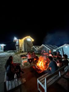 a group of people sitting around a campfire at night at Parashar lake Fogg hill Resort in Prashar lake +59 photos