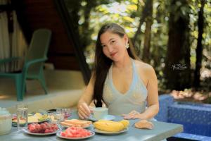 une femme assise à une table avec un plateau de nourriture dans l'établissement Kandy Little White House Cabanas, à Kandy