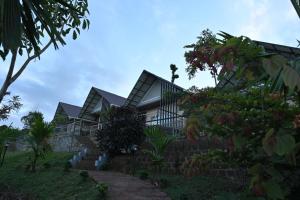 een huis op een heuvel met bomen op de voorgrond bij Banasura Cradle Premium Pool Resort in Wayanad