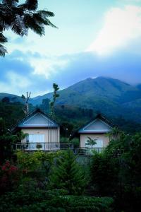 dos casas en una colina con montañas en el fondo en Banasura Cradle Premium Pool Resort, en Wayanad