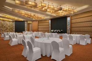 a banquet hall with white tables and chairs and a chandelier at Meluha The Fern Mumbai, Powai, Series by Marriott in Mumbai