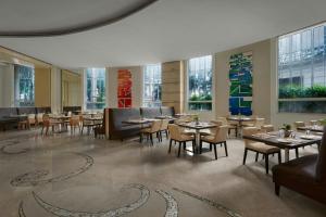 uma sala de jantar com mesas, cadeiras e janelas em Meluha The Fern Mumbai, Powai, Series by Marriott em Mumbai