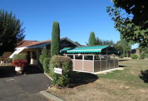 een gebouw met een groene luifel in een tuin bij Abbys Hotel in Sarlat-la-Canéda