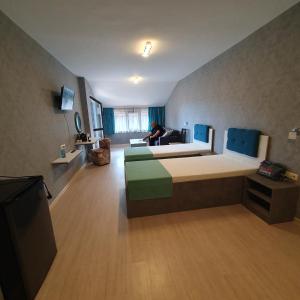 ein großes Zimmer mit einem Bett und einer Person, die auf einem Sofa sitzt. in der Unterkunft Lake View Deluxe Tryavna in Trjawna