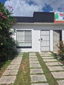 une maison blanche avec deux portes et un chemin dans l'établissement Casa Héroes, à Cancún