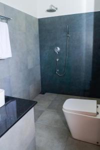 een badkamer met een douche en een wit toilet bij Villa NU 380 in Galle