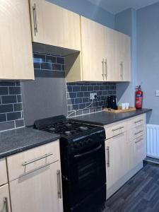 een keuken met een zwarte kachel en witte kasten bij Tyneside Two Bedroom Apart in Gateshead +6 foto's