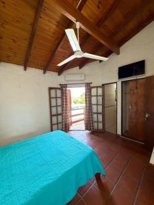 Schlafzimmer mit einem blauen Bett und einem Deckenventilator in der Unterkunft El Amanecer in Mina Clavero