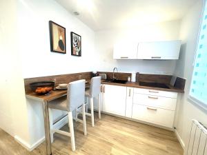a kitchen with a table and chairs and a sink at Studio cosy refait à neuf - Parking privé in Lanester
