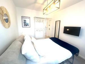 a bedroom with a white bed and a television at Studio cosy refait à neuf - Parking privé in Lanester