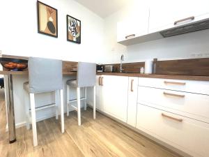 a kitchen with white cabinets and a table and chairs at Studio cosy refait à neuf - Parking privé in Lanester