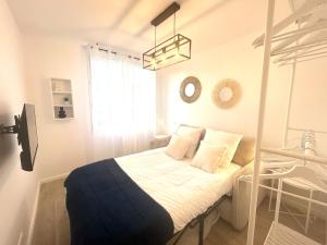 a bedroom with a bed with white sheets and a window at Studio cosy refait à neuf - Parking privé in Lanester