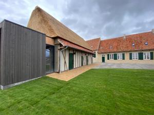 an exterior view of a building with a thatched roof at Eikenbrand in Veurne +4 photos