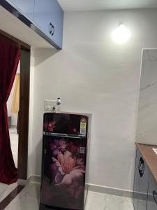 a refrigerator with flowers painted on it in a kitchen at Next Nest in Gannavaram