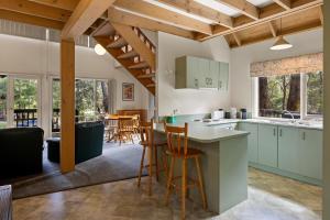 an open kitchen with green cabinets and wooden ceilings at Settle @ Sawmill in Mount Buller