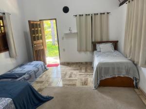 a room with two beds and a door to a room with a window at Chalé Mirante do Lago Cotijuba in Belém