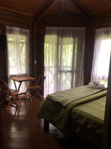 a bedroom with a bed and a table and windows at Refugioecolodge in Nova Friburgo +21 photos