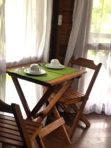 a wooden table with two cups and plates on it at Refugioecolodge in Nova Friburgo