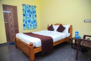 a bedroom with a wooden bed with white sheets and pillows at JR Residency in Usilampatti +10 photos