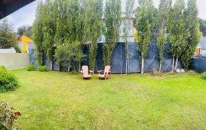 two benches in a yard with trees and a fence at Las Margaritas in Ushuaia