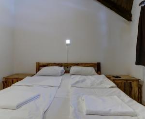 twee bedden in een kamer met witte lakens bij Srna Etno Selo - Hotel i Restoran in Inovo