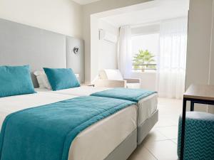 a hotel room with two beds and a window at Hotel Atismar in Quarteira