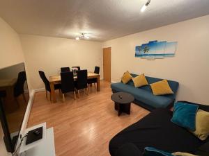 a living room with a blue couch and a table at 2 Bedroom Ground Floor Flat with Kitchen & Parking in Uxbridge
