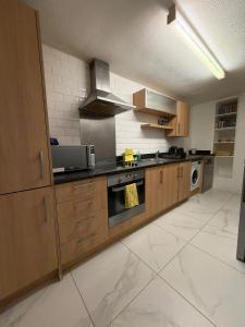 a kitchen with wooden cabinets and a stove top oven at 2 Bedroom Ground Floor Flat with Kitchen & Parking in Uxbridge +11 photos