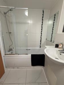 a bathroom with a tub and a sink and a shower at 2 Bedroom Ground Floor Flat with Kitchen & Parking in Uxbridge