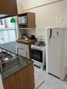 a kitchen with a white refrigerator and a stove at Studio Sereno in Barbacena