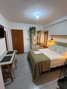 a bedroom with a bed and a table and a desk at Studio Sereno in Barbacena