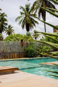 une piscine avec des palmiers et une clôture dans l'établissement Casa Vilas Patacho Garden, à Porto de Pedras