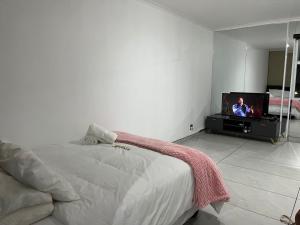 a bedroom with a bed and a flat screen tv at Malibu Dream in Gqeberha