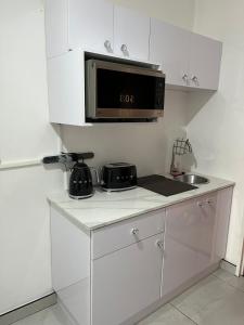 a white kitchen with a microwave and a sink at Malibu Dream in Gqeberha