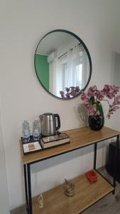 een tafel met een spiegel en een vaas met bloemen erop bij Donna Giovanna Guest House in Cosenza