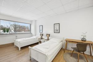 a white living room with two white couches and a table at HanseStay Wandsbek in Hamburg