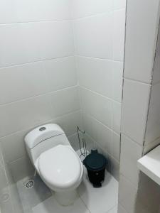 een badkamer met een wit toilet en een zwarte emmer bij Pousada Montblanc suíte 4 in Guarujá