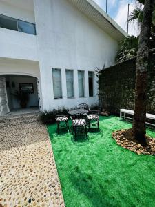 a patio with a table and chairs on grass at Pousada Montblanc suíte 4 in Guarujá