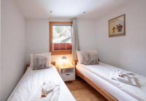 two beds in a small room with a window at Chalet Waldschluecht in Wengen