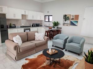 a living room with a couch and two chairs and a table at Mtunzini South Cottage in Mtunzini
