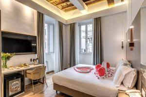 een slaapkamer met een bed, een bureau en een televisie bij Relais Trevi 95 Boutique Hotel in Rome